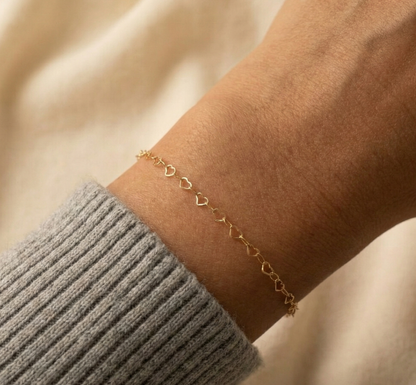 Gold bracelet on a wrist with a neutral background